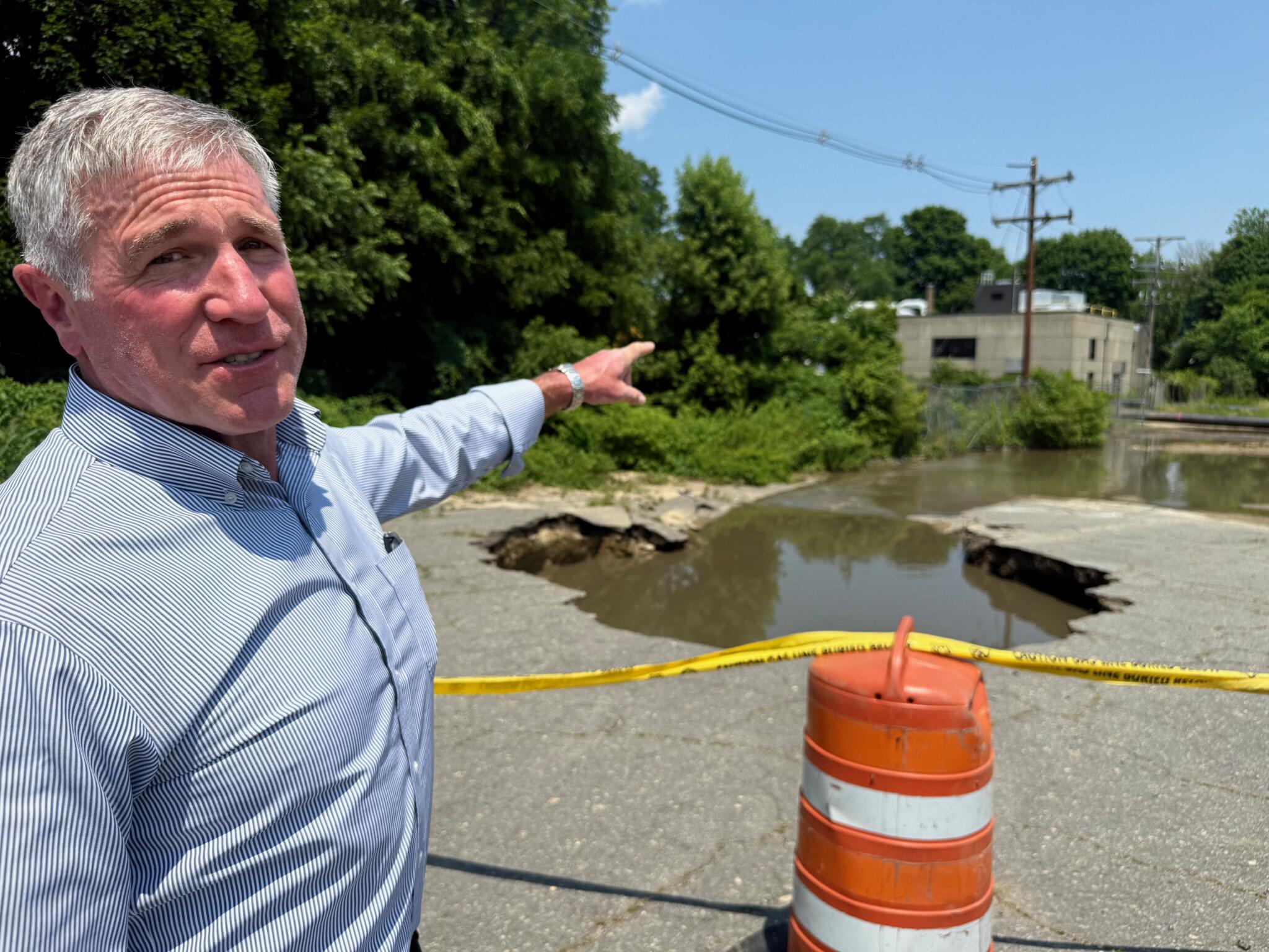 Bob Ward, Haverhill’s water and wastewater director, points to the area where the sewer line broke Friday evening during a heavy rainstorm. (Miriam Wasser/WBUR)