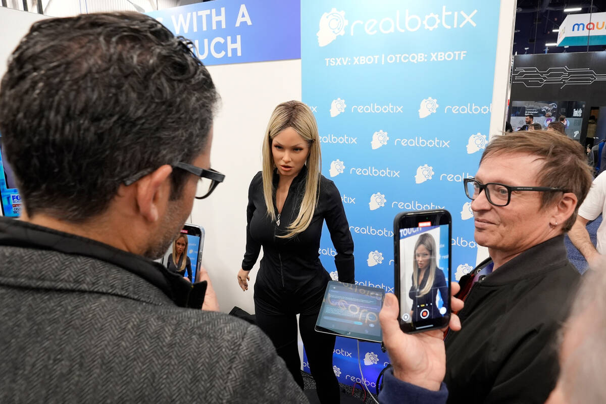 FILE - A Realbotix humanoid robot, center, speaks with attendees at a Realbotix booth during th ...