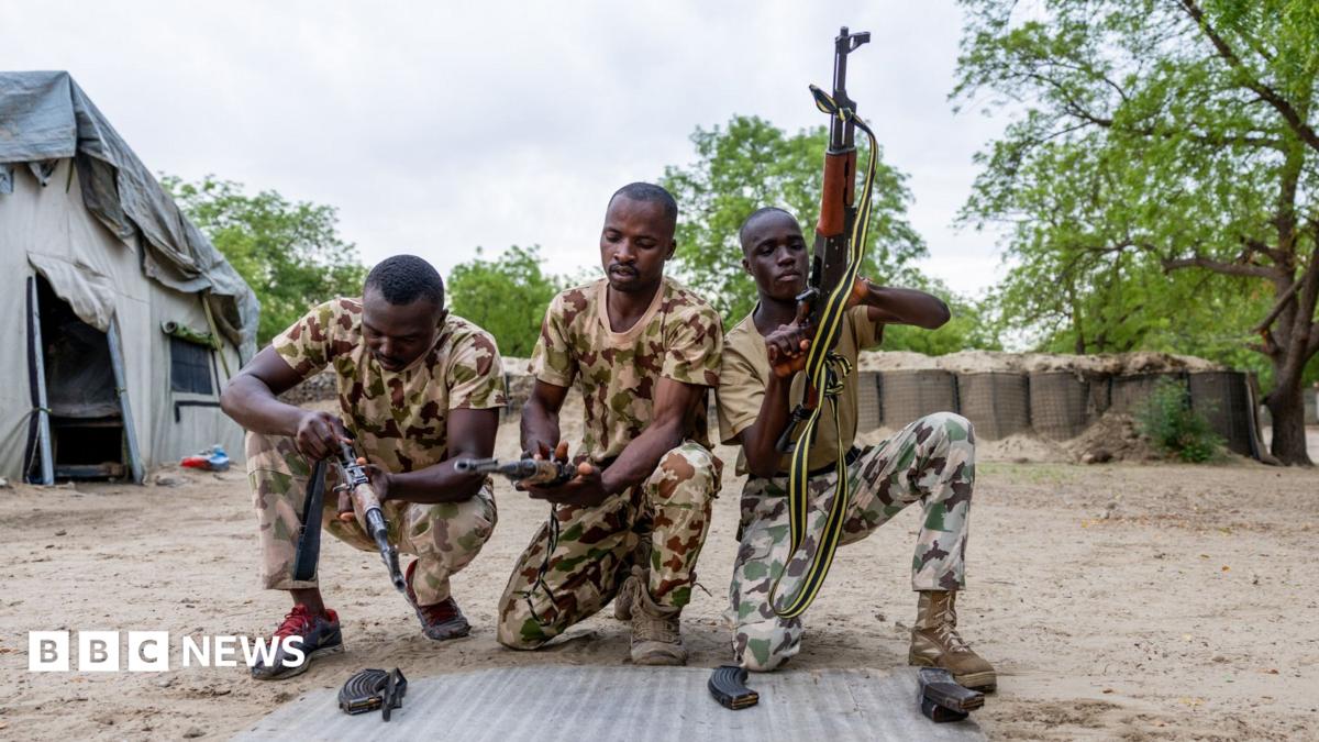 Three Nigerian soldiers wearing army fatigues appear to load their guns