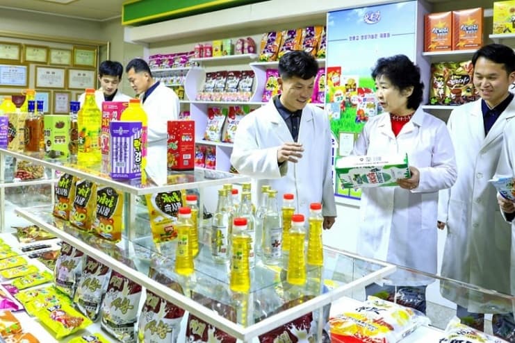 Workers in white lab coats inspect food products on display at the Amnok River General Food Factory in North Korea.