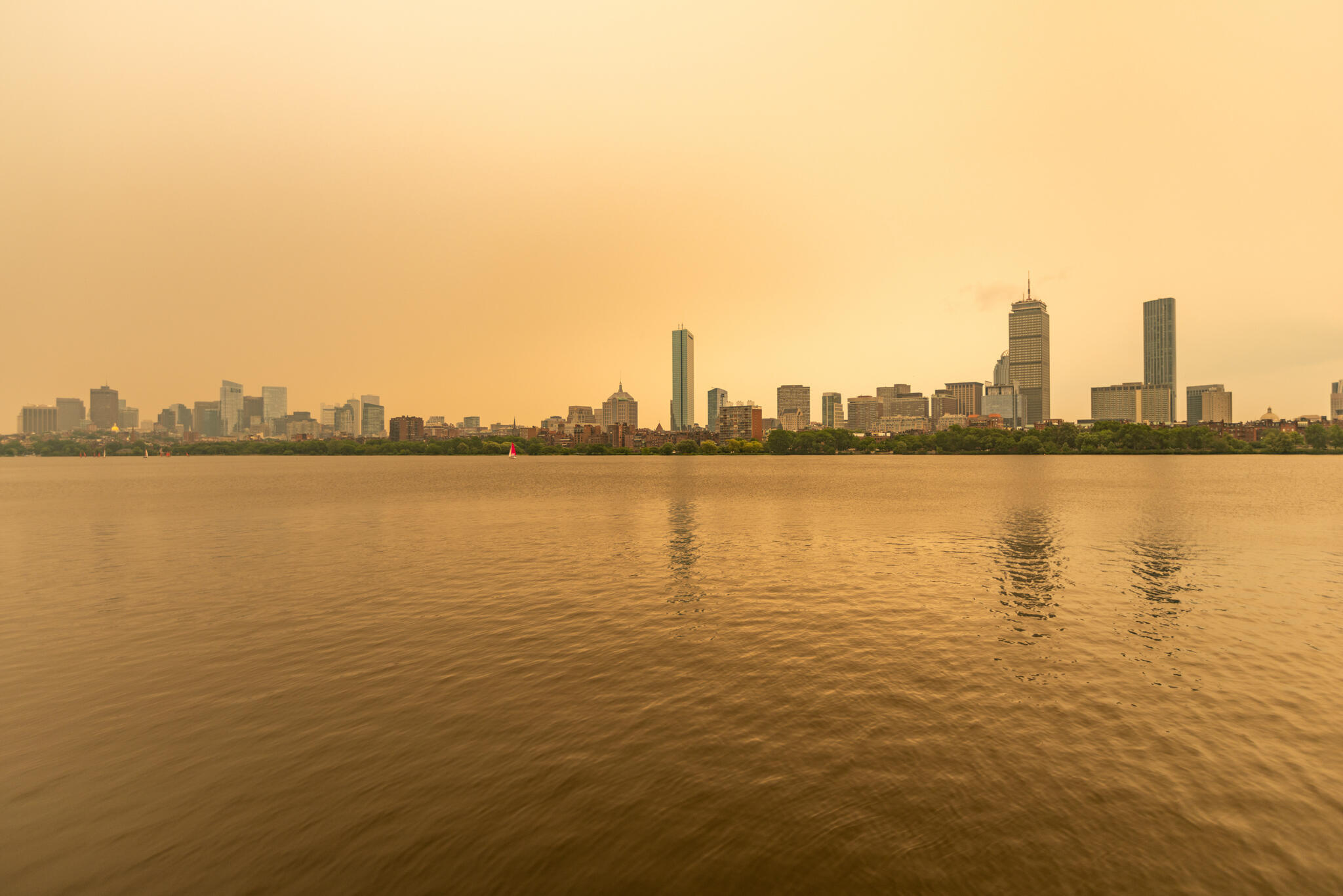 The Boston skyline along the Charles River as seen around noon on Wednesday as wildfire smoke from Canada creates a yellow haze. (Jesse Costa/WBUR)