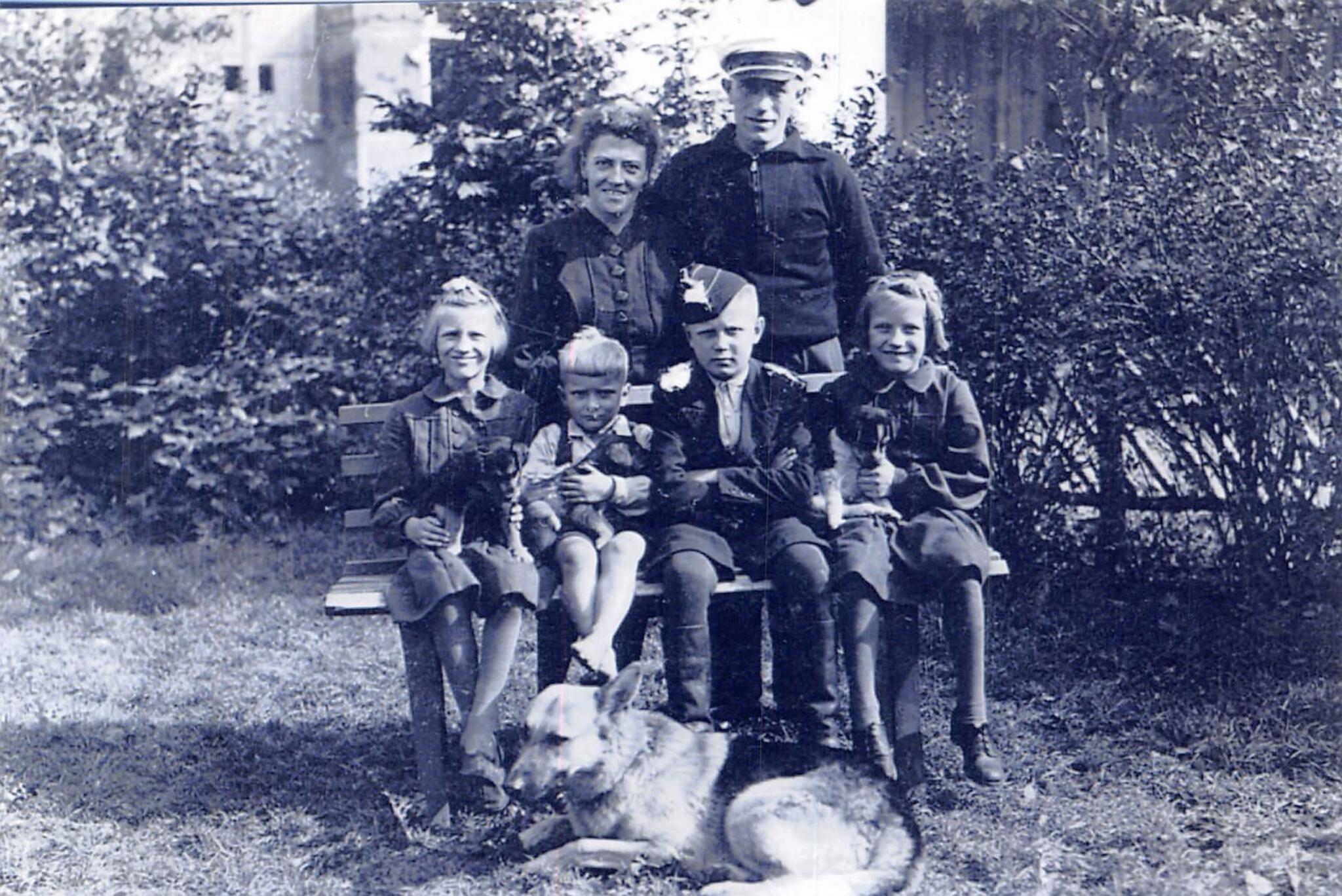 The author’s father pictured center at age 11 or 12, sitting on a bench with arms crossed, Herr Kroutsick and family surrounding him, Minsk, Belarus, 1942. (Courtesy Jason Prokowiew)