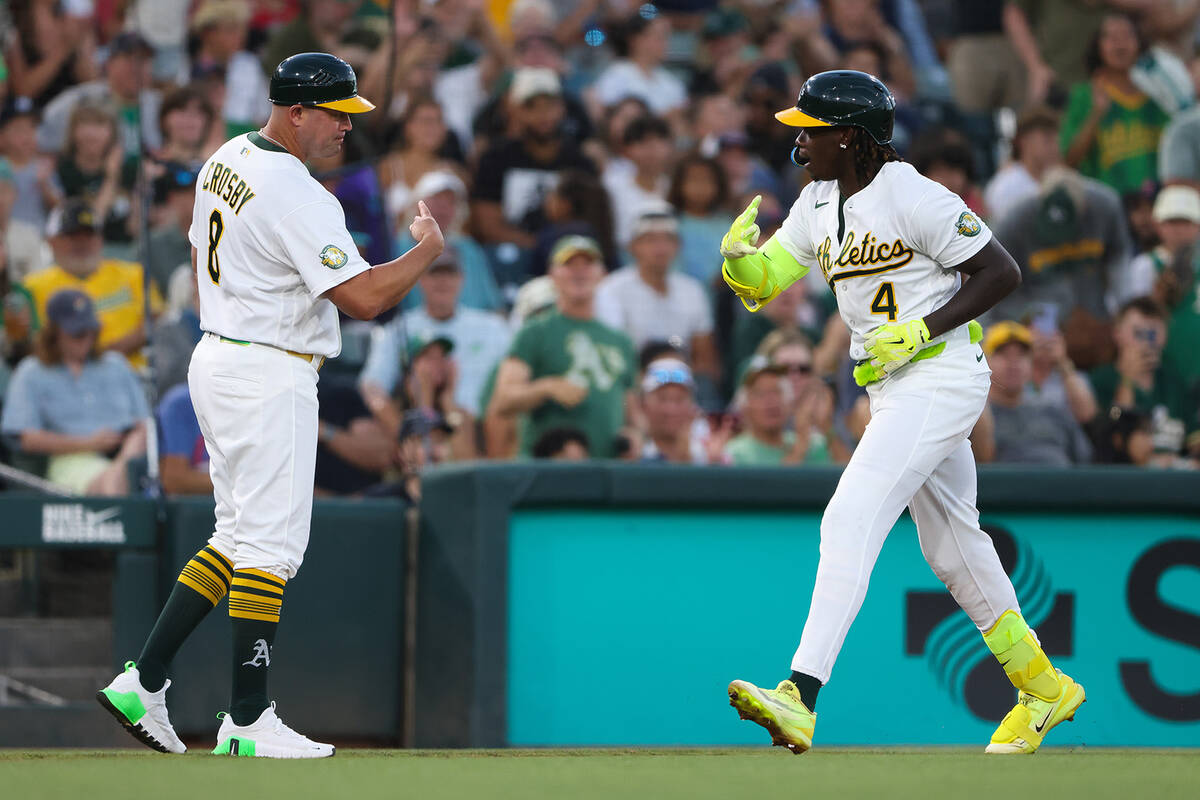 Athletics' Lawrence Butler (4) celebrates a with third base coach Bobby Crosby (8) after h ...