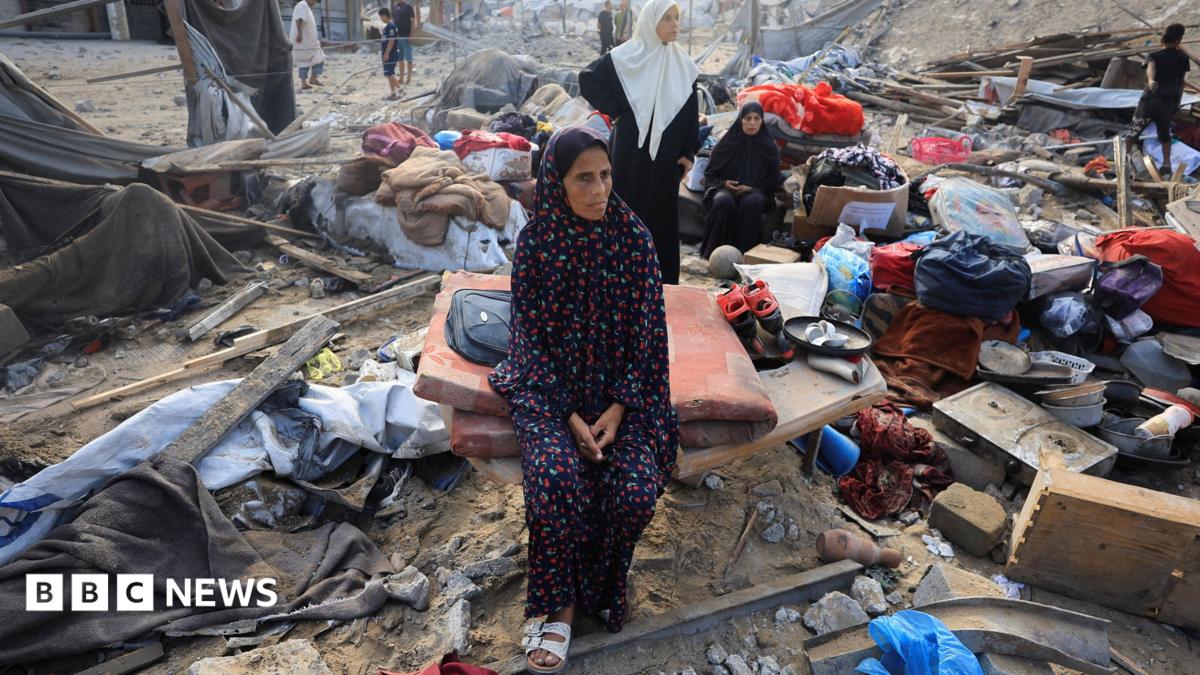A Palestinian woman sits amidst debris as people inspect the site of an Israeli strike on a house in Gaza City, 30 July 2026.