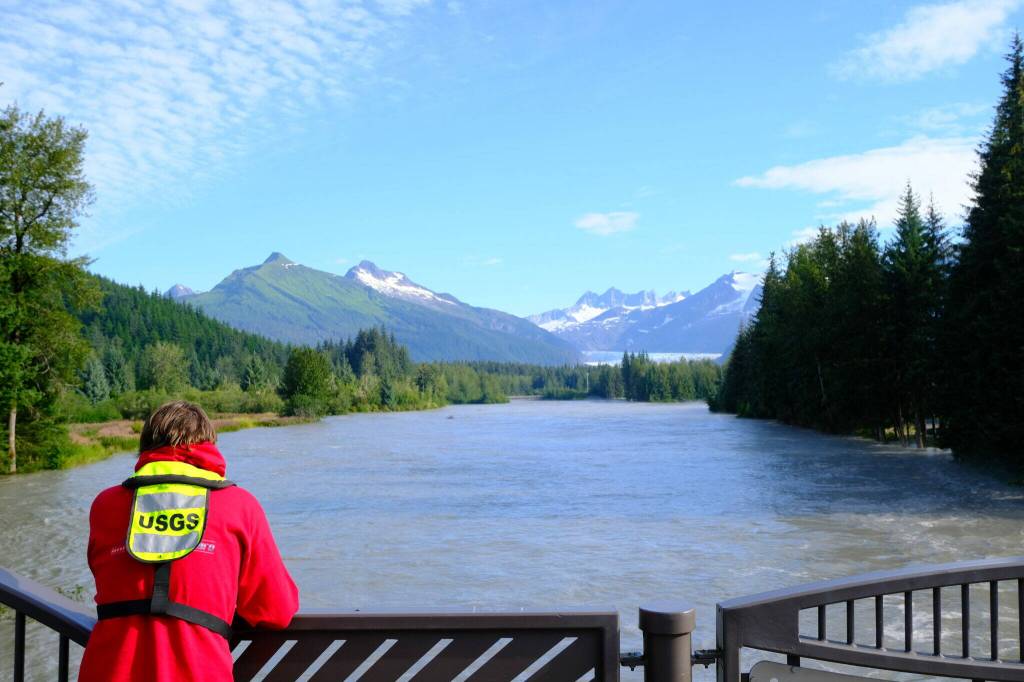 A U.S. Geological Survey worker views the flooding Mendenhall River from the Brotherhood Bridge following the glacial outburst event on Aug. 13, 2025. (Photo by Corinne Smith/Alaska Beacon)