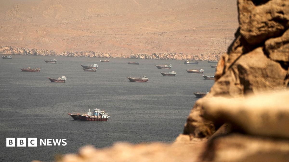 A file photo shows vessels in the straight as pictured from Oman in April, with bokeh Omanian boulders in the foreground and Iranian desert in the background.