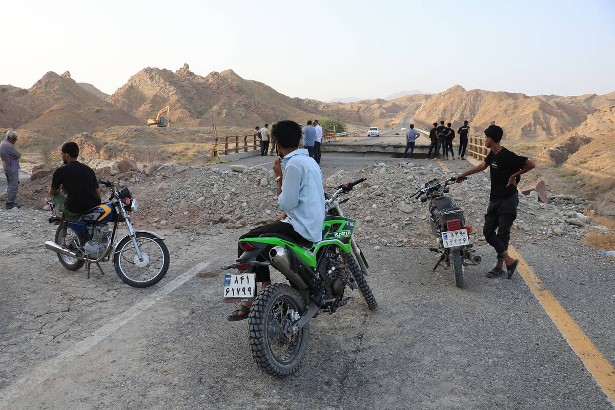 People stand on a bridge destroyed after a strike in Hormozgan province, southern Iran, Saturda ...