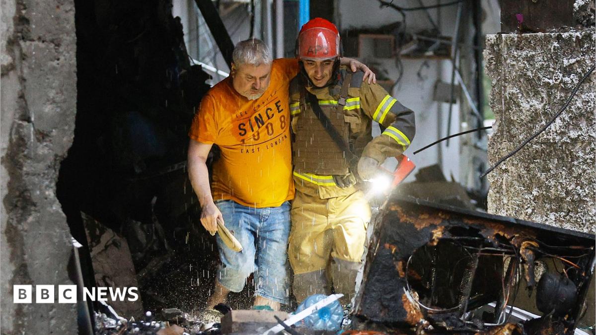 Sarah Rainsford in a brown shirt with short sleeves in front of rubble in Kyiv