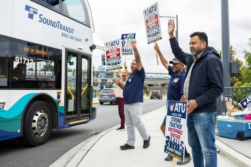 Maxwell Lall (right to left), Tadesse Yeglatu, Jaswinder Bains and Tara Wickenburg, with a dozen other ATU Local 1576 members, picket on the corner of 200th Street Southwest and 46th Avenue West for fair contracts for transit workers on Friday, July 17, 2026 in Lynnwood, Washington. (Olivia Vanni / The Herald)
