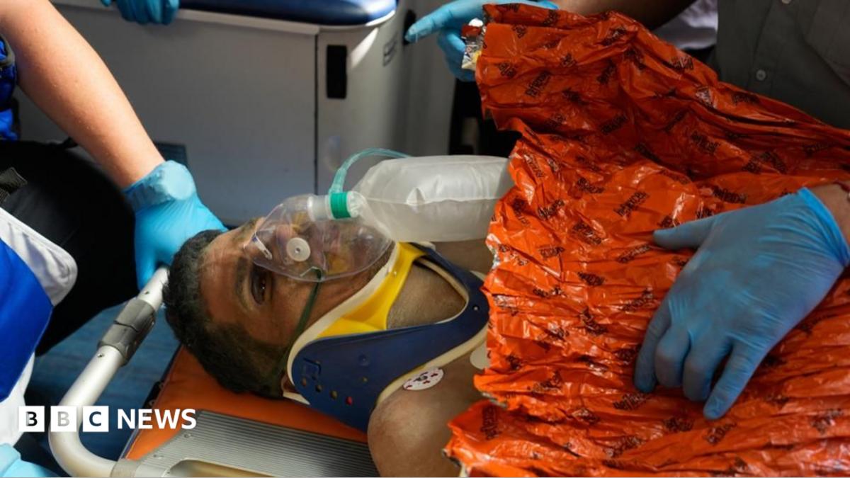 Hernán Gil is seen with an oxygen mask, a neck collar and wrapped in an orange blanket, on a stretcher