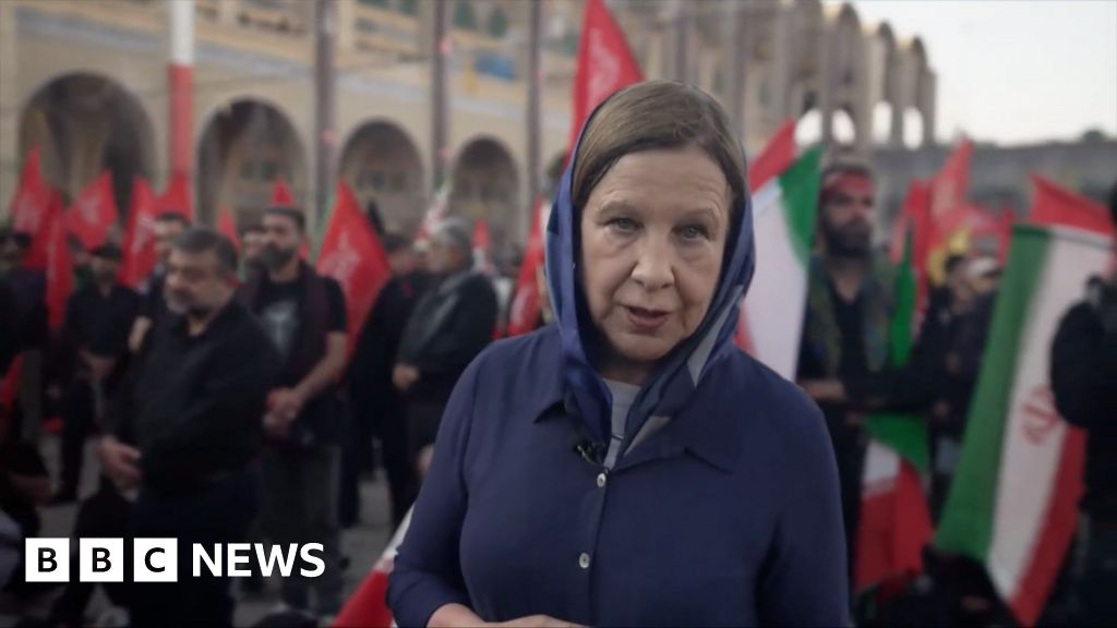 Lyse Doucet looks into the camera as she stands among a crowd carrying Iranian flags