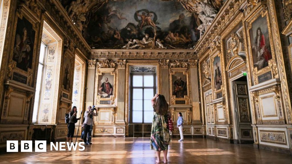 A visitor takes a picture in the Apollo Gallery during its reopening at the Louvre Museum