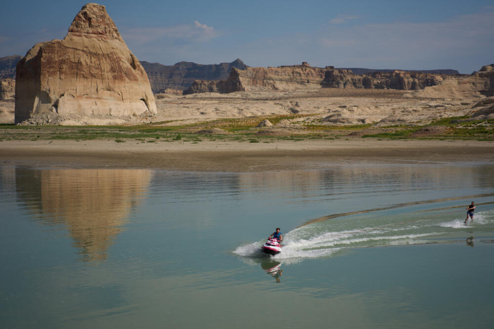 Vitalii Volna drives a jet ski on Lake Powell at the Glen Canyon National Recreation Area, Wednesday, July 15, 2026, near Big Water, Utah. A bathtub ring of light minerals shows the high water mark of the lake. (John Locher/AP)