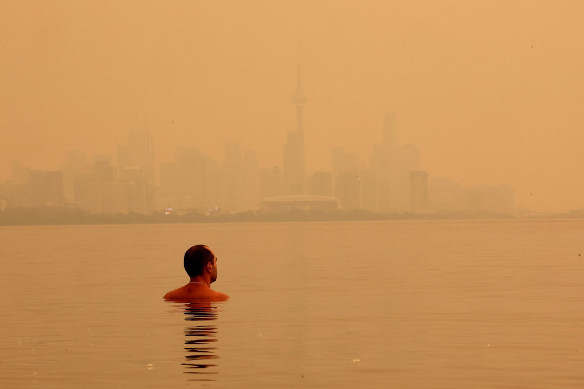 Steve Russell/Toronto Star/Getty Images via CNN NewsourceA swimmer checks out the view of the smoke from Northern Ontario forest fires that has the City of Toronto skyline shrouded in haze as viewed from Humber Park West in Toronto