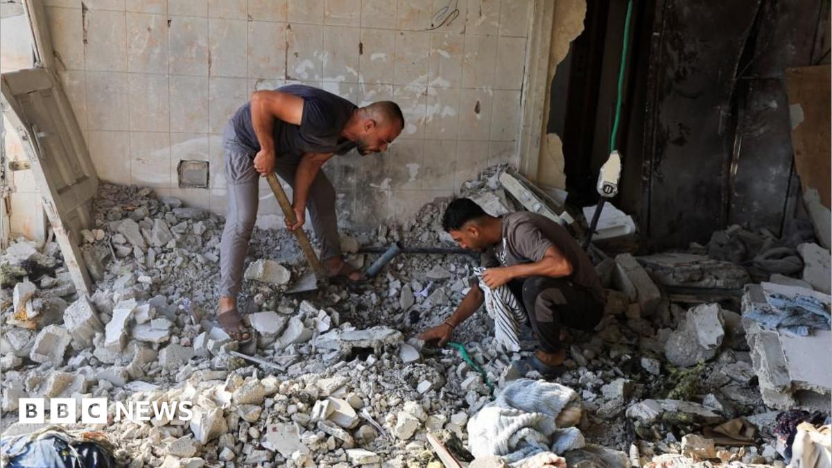 Two men search through rubble