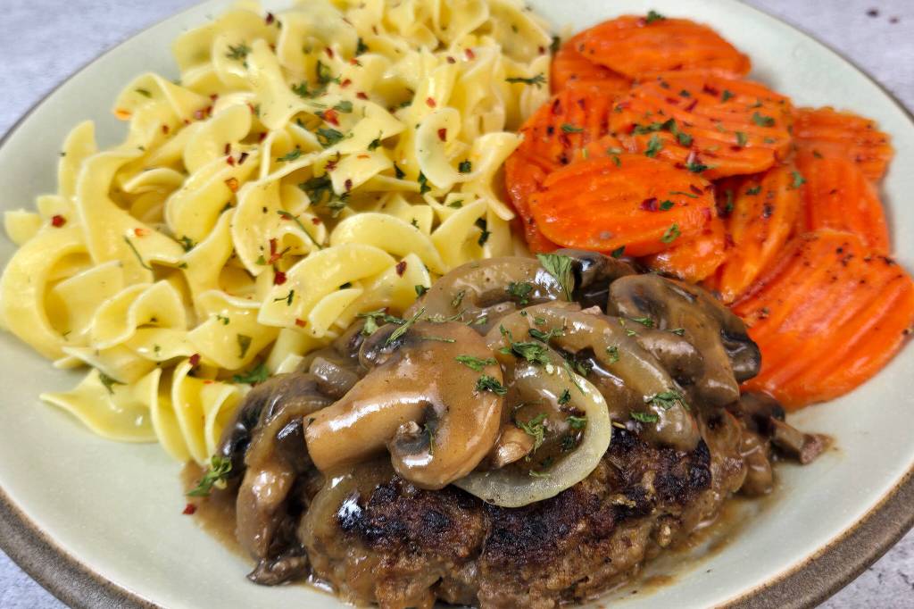 Well-seasoned ground beef steak with homemade mushroom-and-onion gravy, served with garlic butter egg noodles and brown sugar-honey carrots. It’s a complete comfort-food dinner for about $5 per serving. (Roy Mosby)