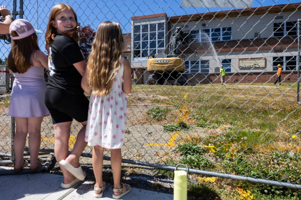 People gather to watch the start of demolition of Jackson Elementary School along Federal Avenue on Thursday, July 30, 2026 in Everett, Washington. (Olivia Vanni / The Herald)