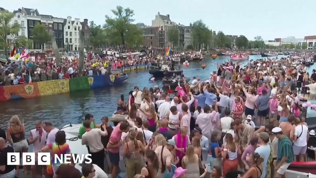 Revellers line Amsterdam canal to watch the annual Pride boat parade