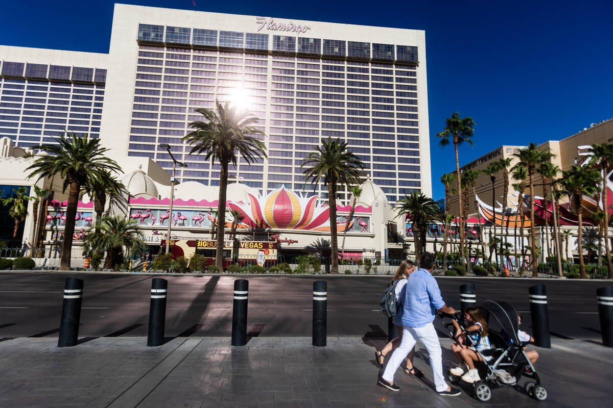 People walk on the strip as temperatures reach 107 degrees Fahrenheit on Tuesday, July 7, 2026, ...