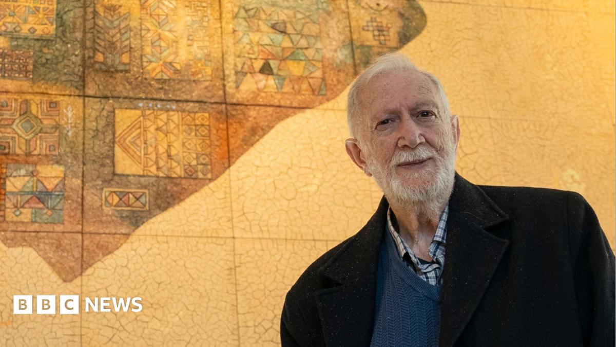 Sliman Mansour stands in front of his artwork, On the Wing of an Angel, Part of the Palestinian Museum Permanent Collection, in Birzeit, in the occupied West Bank