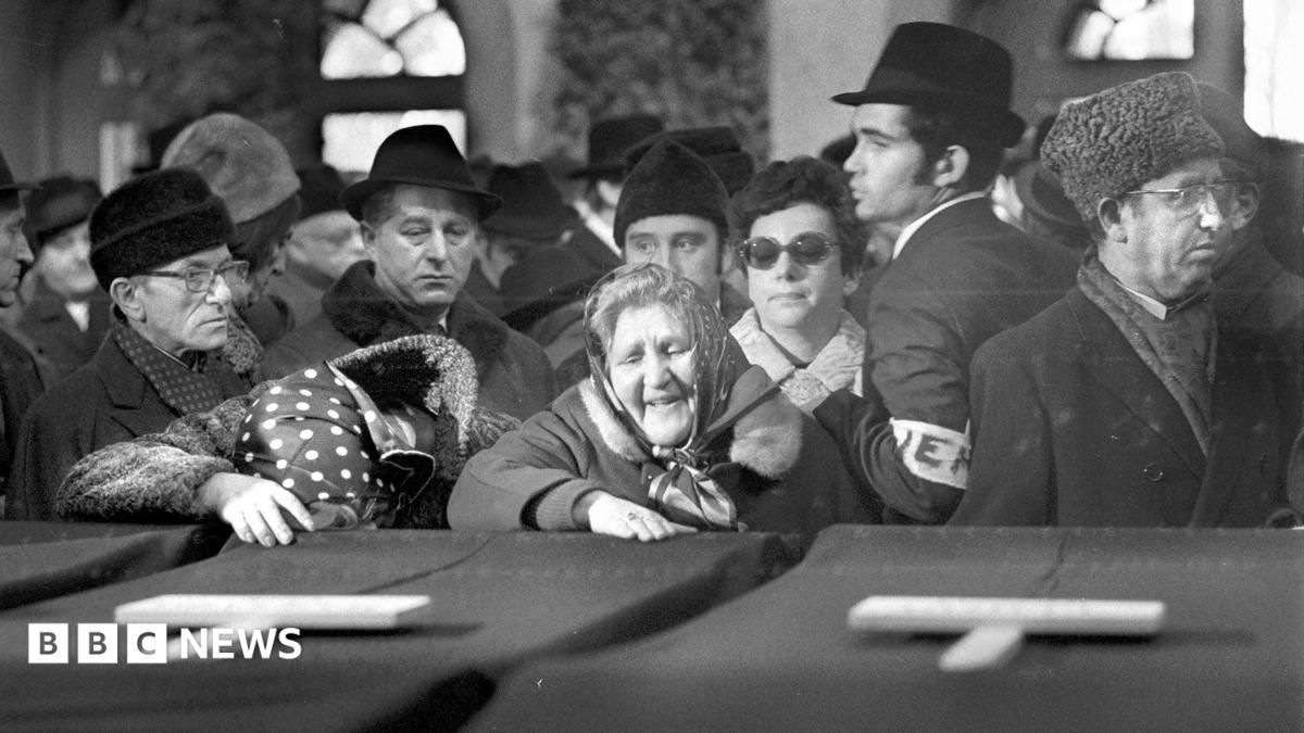 Women mourn the victims in a black and white photo showing coffins