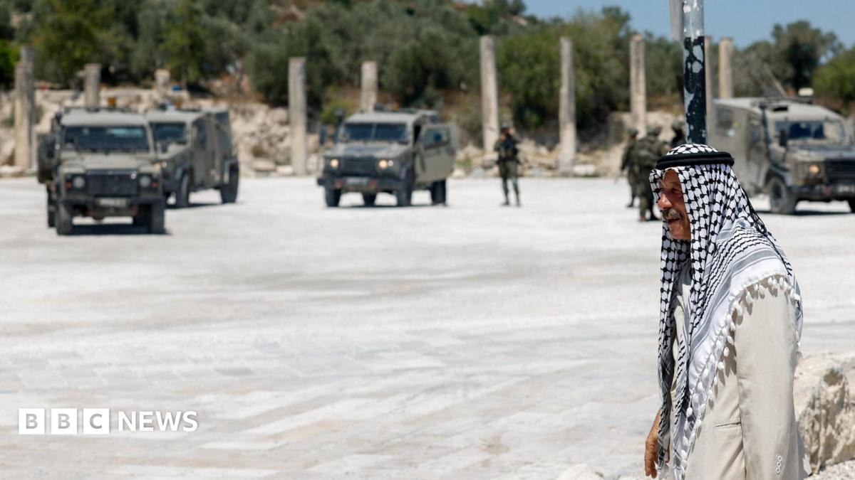 A Palestinian man walks near Israeli troops at the archaeological site of Sebastia, in the occupied West Bank (29 June 2026)