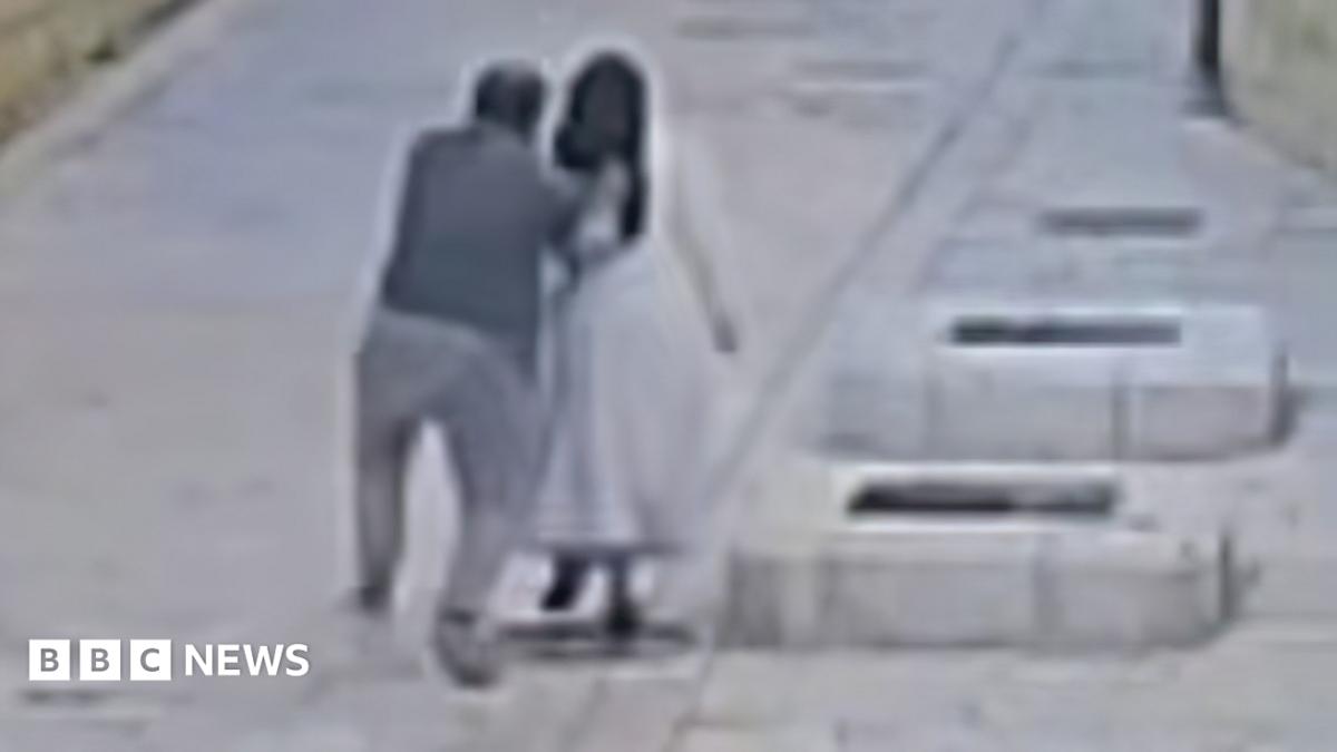 Grainy image from CCTV of a man from behind reaching out to push a nun as both walk in a street in Jerusalem (28/04/26)