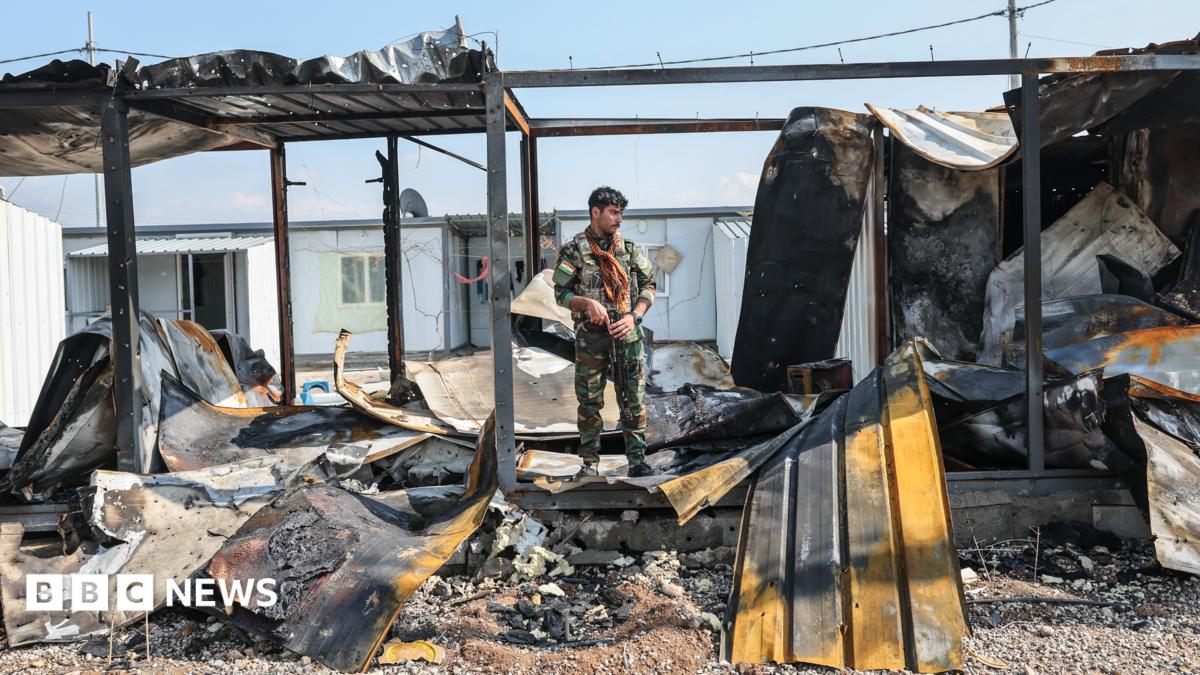 A member of Kurdistan Freedom Party stands next to damaged containers at their military base in Irbil, Iraq, after Iranian drone attack in March