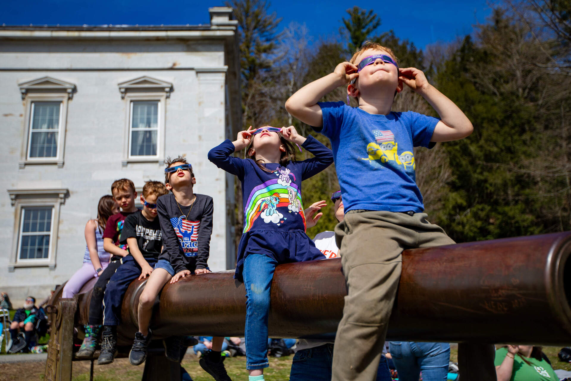 Kids watch a total eclipse in front of the Vermont State Montpelier on April 8, 2024. (Jesse Costa/WBUR file)