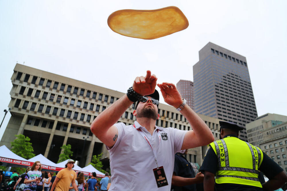 Anthony Pilla flings a pizza skyward over City Hall Plaza at the Boston Pizza Festival. (John Tlumacki/The Boston Globe via Getty Images)