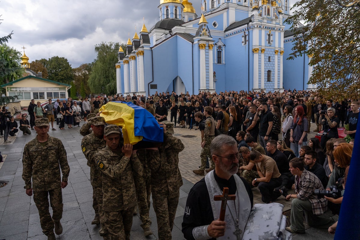 A pregnant soldier mourns her 21-year-old husband at his funeral in Ukraine