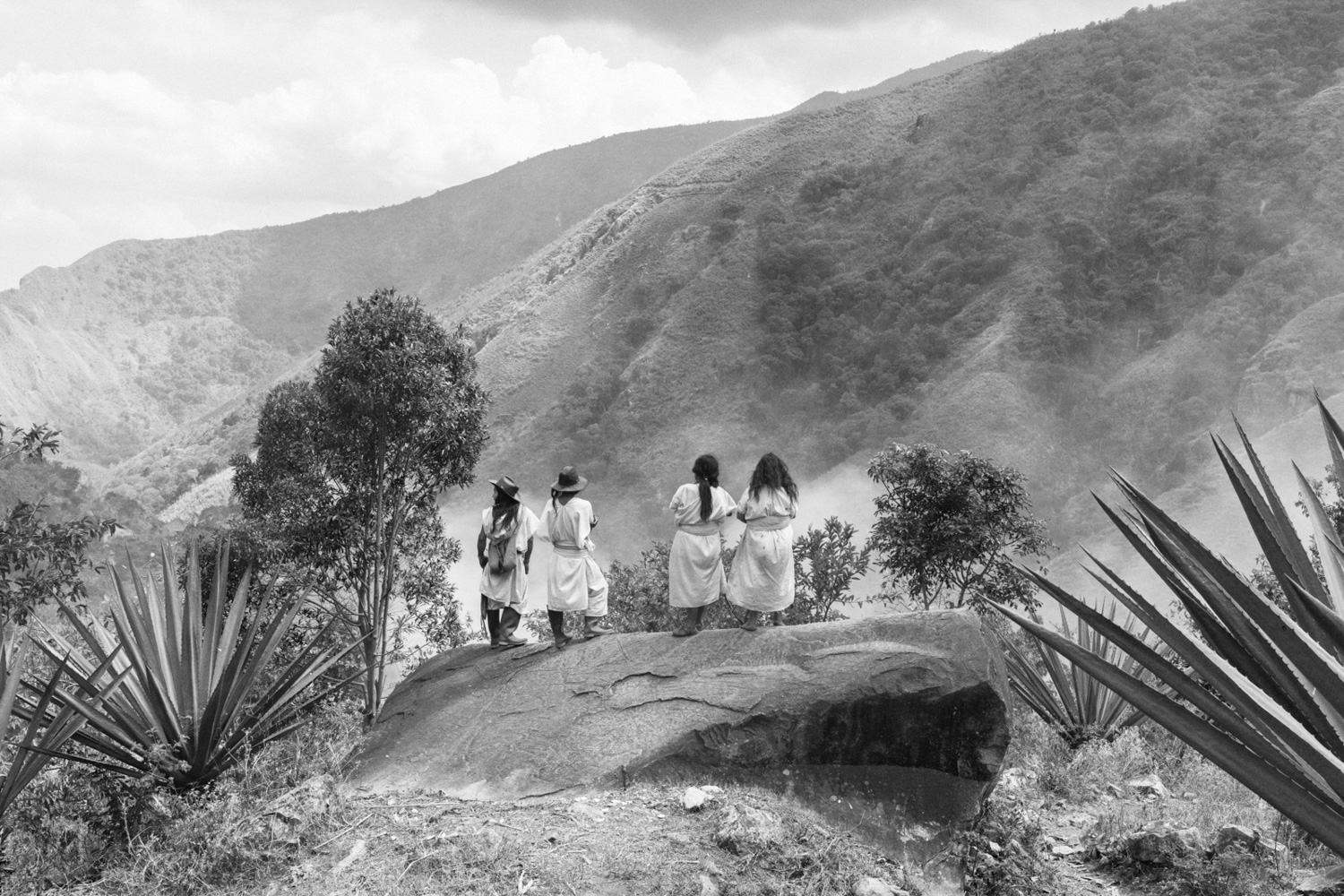 Members of the Arhuaco community observe a fire that threatens their homes, Donachuì, Sierra Nevada de Santa Marta 2025. The transition between the dry and rainy seasons has become increasingly unstable, resulting in strong winds that can cause small fires, typically set to manage weeds, to spiral out of control. Image by Roberto Maccariello.