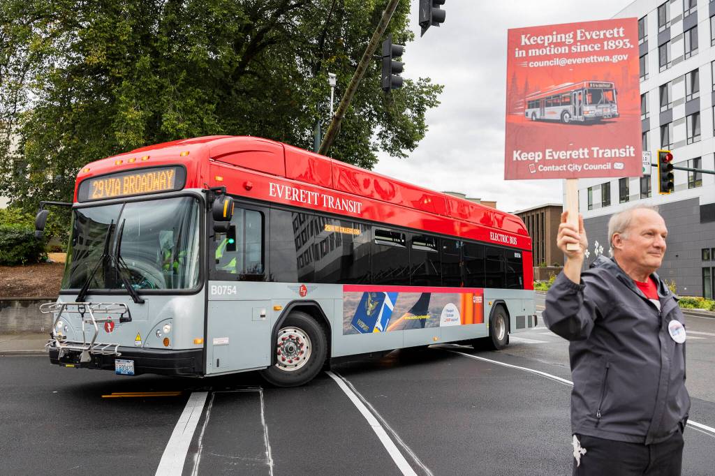 Karl Nueue-Lawson, a paratransit operator, stands on the corner of Wetmore Avenue and Pacific Avenue before an Everett City Council meeting on Wednesday, Sept. 2, 2026, to protest the possible merger between Everett Transit and Community Transit in Everett, Washington. (Olivia Vanni / The Herald)