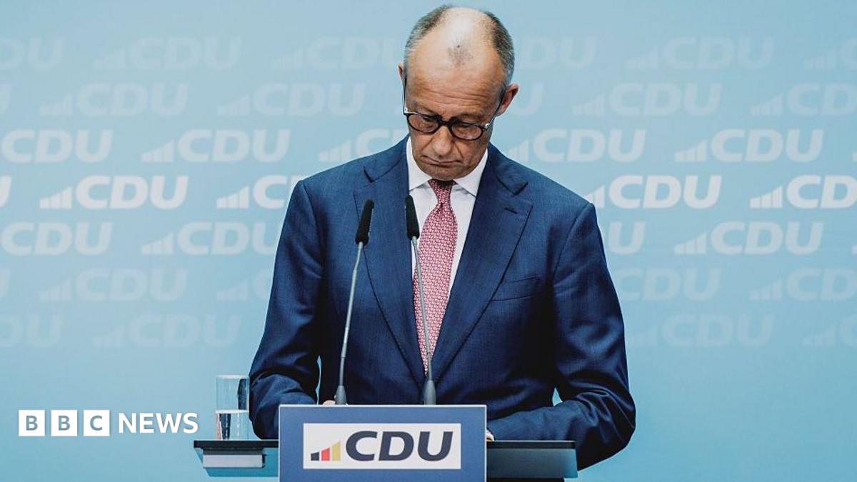 Friedrich Merz looking down at podium bearing the logo of his political party, the CDU