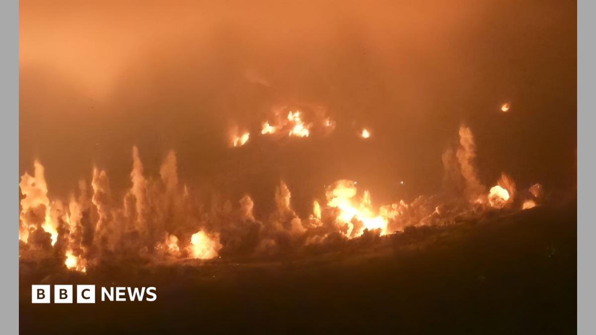Huge flames and pillars of smoke rise from the ground in a night-time picture