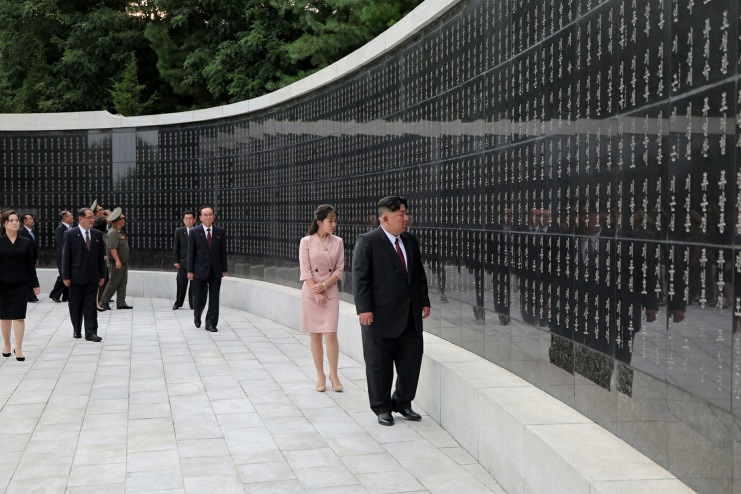 Kim Jong Un and Kim Ju Ae walk past a wall inscribed with names at the Taesong Mountain Revolutionary Martyrs' Cemetery in Pyongyang, flanked by North Korean officials, during an Aug. 14 visit marking the 81st anniversary of Korea's liberation.