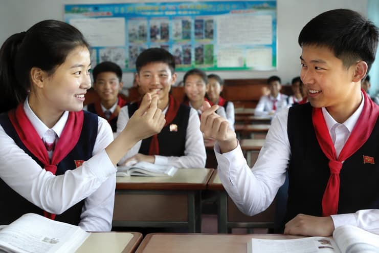 North Korean students in school uniforms exchange finger heart gestures in a classroom