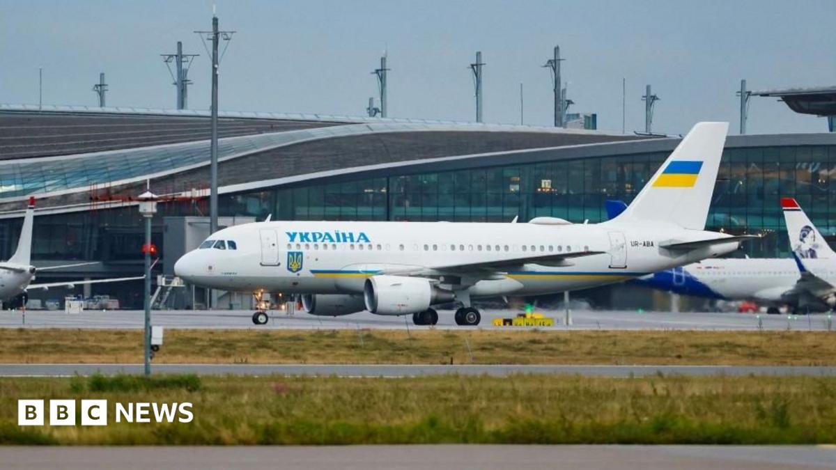 A white painted passenger plane sits on a runway at an airport after landing