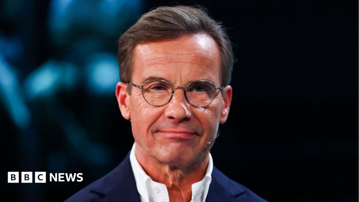 Ulf Kristersson, who has short brown hair and round glasses, poses for the cameras in a TV studio before a debate ahead of the election