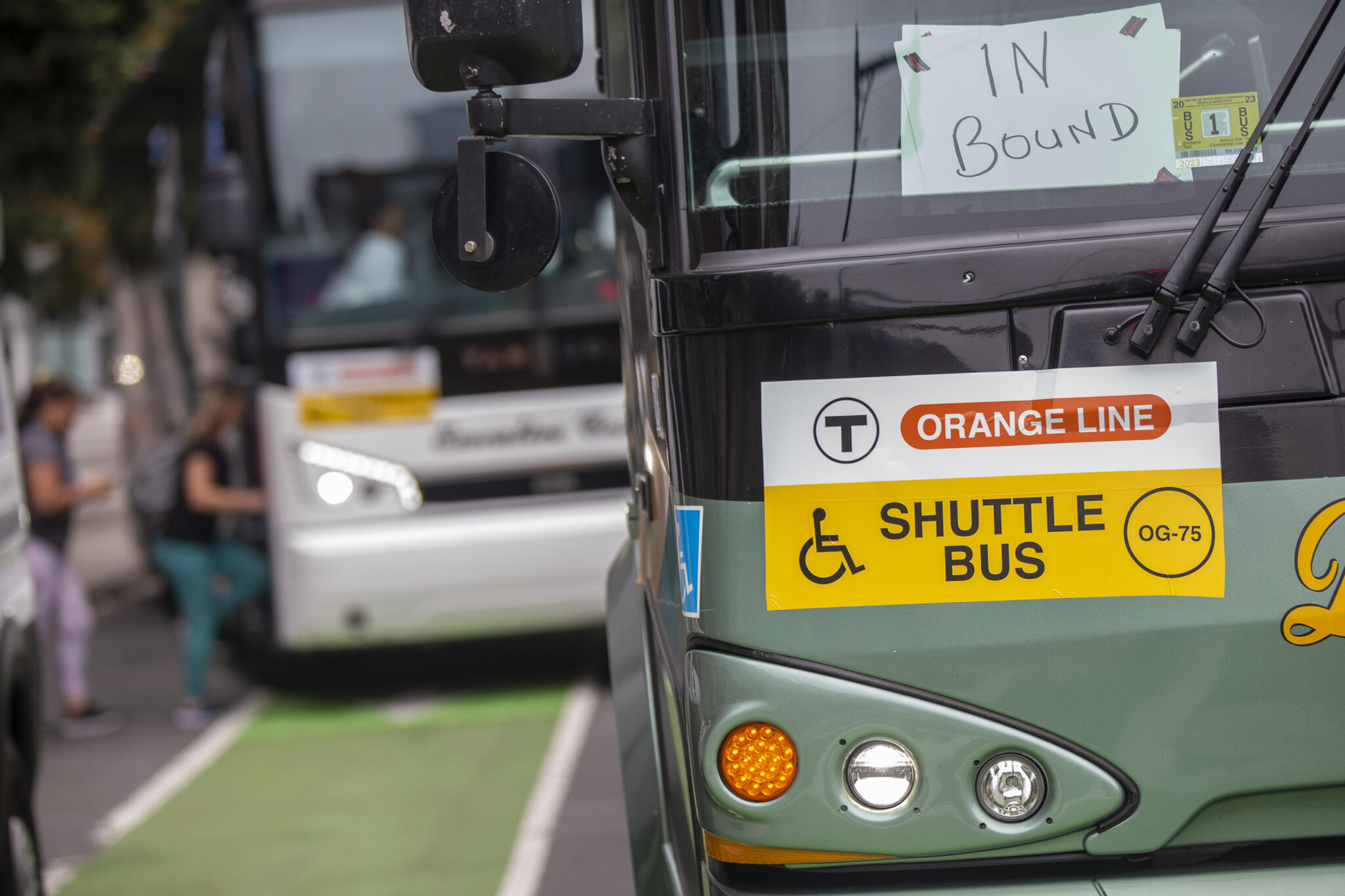 Commuters board an MBTA Orange Line shuttle bus as other buses wait at North Station. (Jesse Costa/WBUR, file)