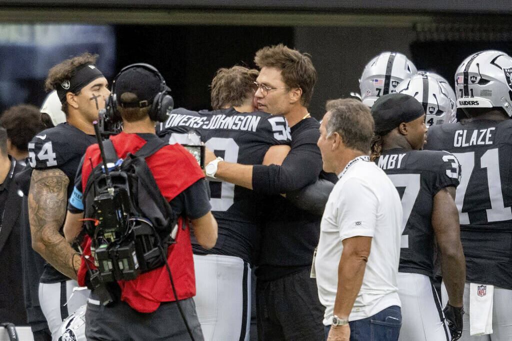 Raiders minority owner Tom Brady hugs Raiders offensive lineman Jackson Powers-Johnson (58) bef ...