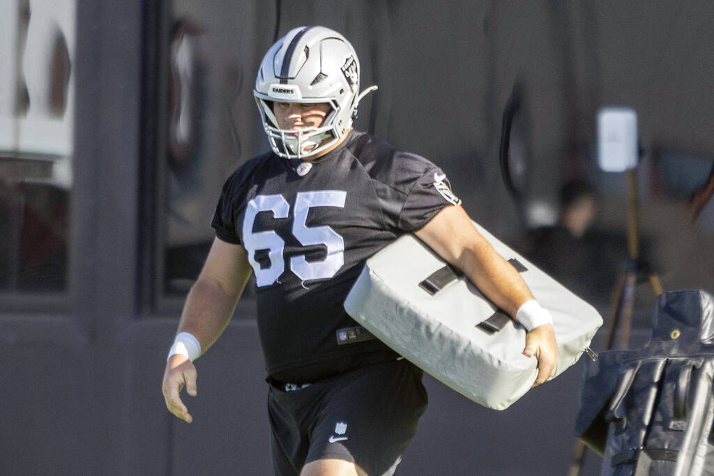 Raiders center Tyler Linderbaum (65) carries a tackle pad during an NFL football training camp ...