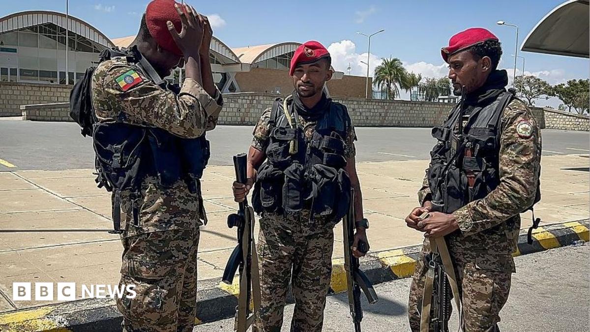 Three members of the Ethiopian National Defense Force (ENDF) in military fatigues and red berets. Behind them is the Mekelle Alula Aba Nega International Airport