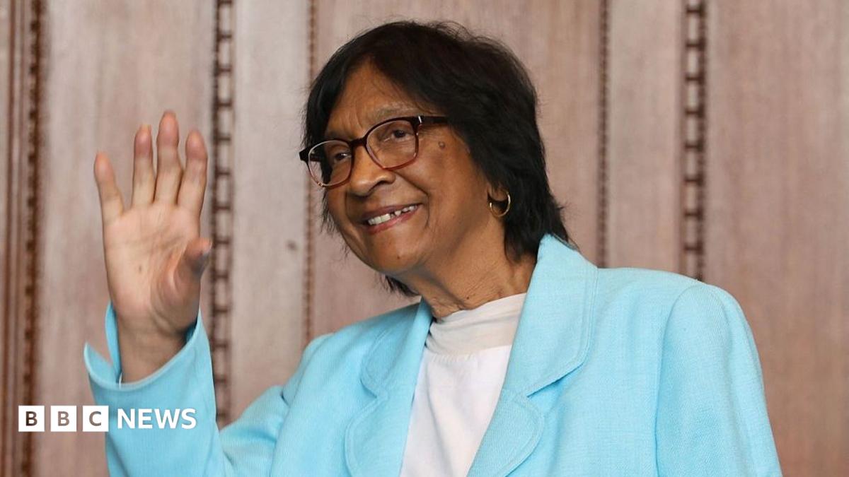 Navi Pillay in a sky blue jacket in front of people congratulating her
