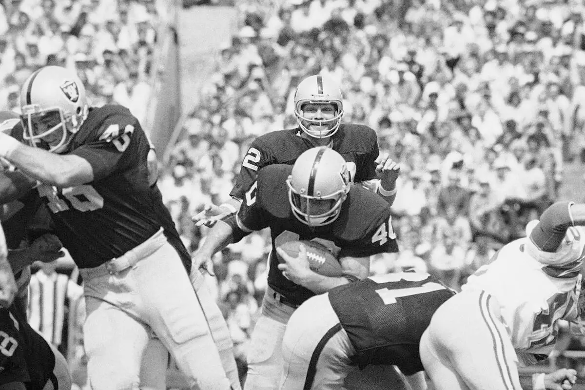 Quarterback Ken Stabler (12) watches with a smile as running back Pete Banaszak (40) plunges in ...