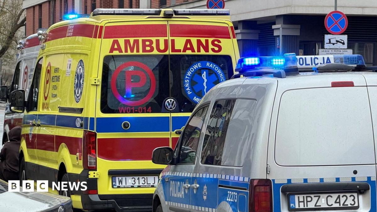 An ambulance of the Polish ambulance service parked in front of a grey Polish National Police van on the side of the road, both have blue sirens on